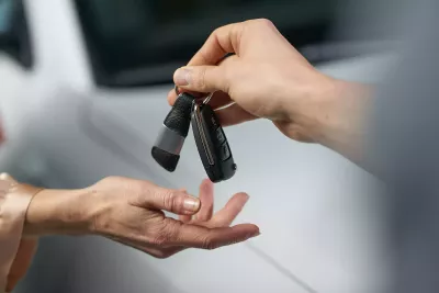 A person handing car keys to another person